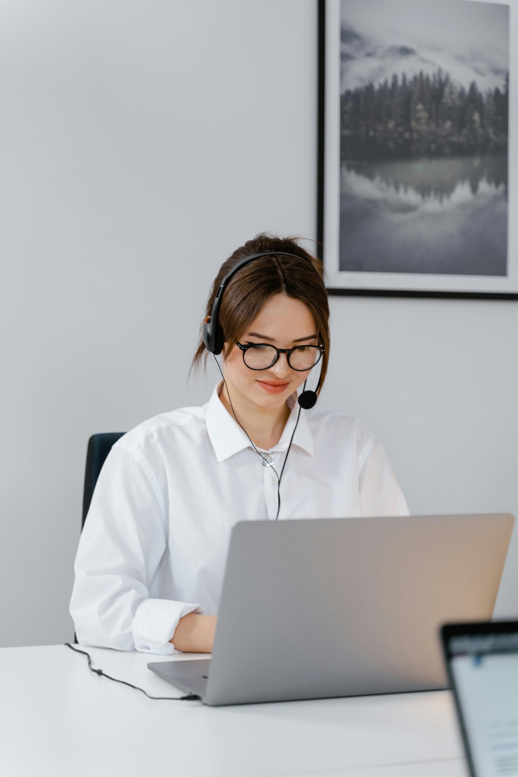 Woman working on laptop with headset.